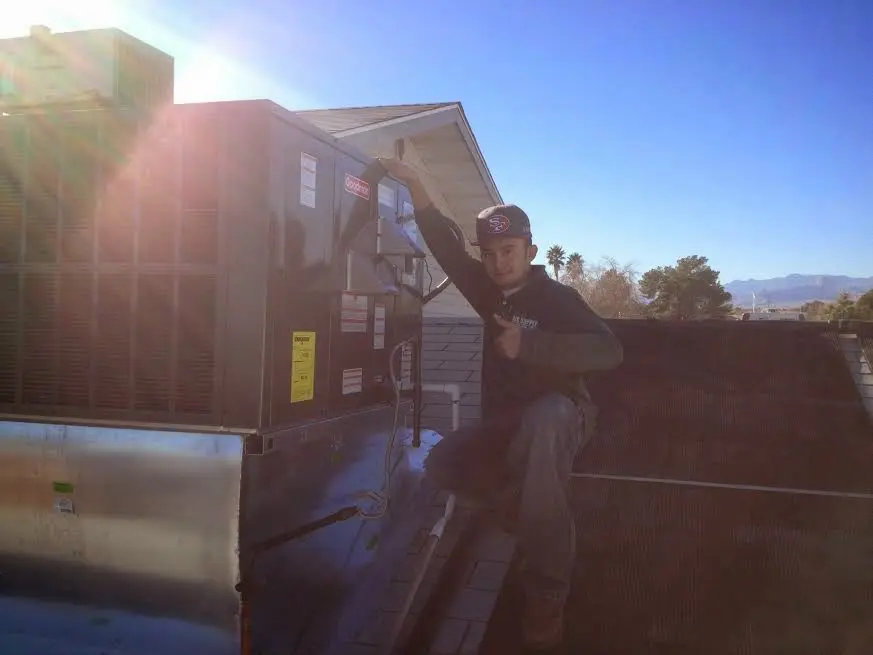 HVAC technician performing Heat Pump Repair on a rooftop unit in Flagstaff